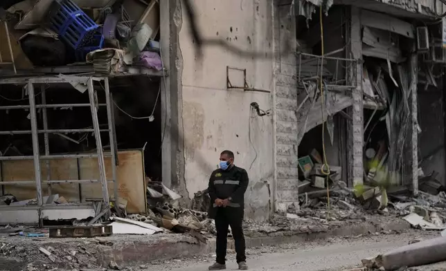 A member of Hezbollah stands guard next to a destroyed building in Dahiyeh, Beirut's southern suburbs, Lebanon, Friday, April 17, 2026, following a ceasefire between Israel and Hezbollah. (AP Photo/Bilal Hussein)