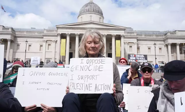 Protesters hold up placards at a demonstration against the ban on Palestine Action, in Trafalgar Square, central London, Saturday April 11, 2026. (Lucy North/PA via AP)