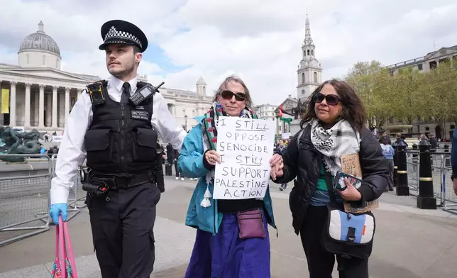 A police officer leads a protester away at a demonstration against the ban on Palestine Action, in Trafalgar Square, central London, Saturday April 11, 2026. (Lucy North/PA via AP)