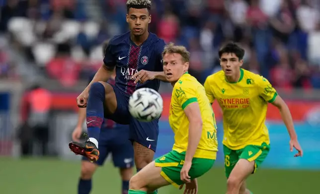 PSG's Desire Doue, left, and Nantes' Nicolas Cozza challenge for the ball during the French League One soccer match between Paris Saint-Germain and Nantes in Paris, France, Wednesday, April 22, 2026. (AP Photo/Michel Euler)