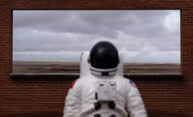 An astronaut figure is placed in front of a window opening at Meteor Crater, an attraction near historic Route 66, near Winslow, Ariz., Thursday, Nov. 20, 2025. (AP Photo/Jae C. Hong)