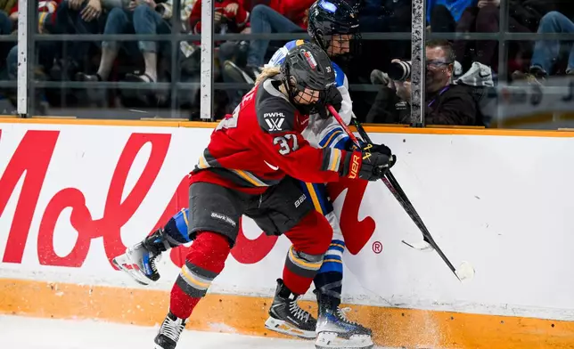 Ottawa Charge's Rebecca Leslie (37) pins Toronto Sceptres' Kali Flanagan (6) against the boards while battling for the puck during the first period of a PWHL hockey game in Ottawa, Ontario, Saturday, April 25, 2026. (Spencer Colby/The Canadian Press via AP)