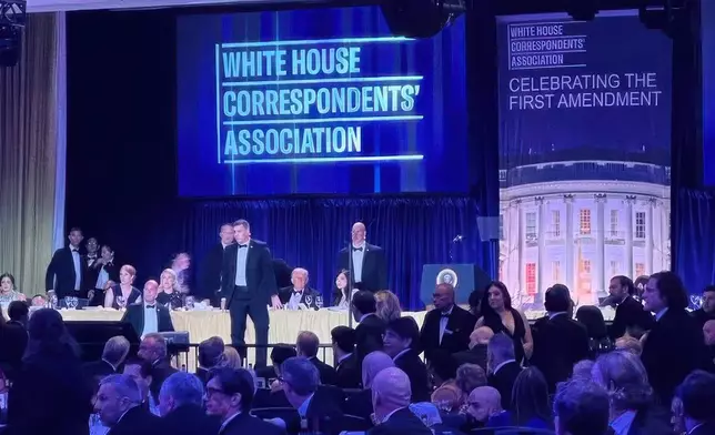 U.S. Secret Service agents surround President Donald Trump as he is taken from the stage after a shooting incident outside the ballroom during the White House Correspondents Dinner, Saturday, April 25, 2026, in Washington. (AP Photo/Alex Brandon)