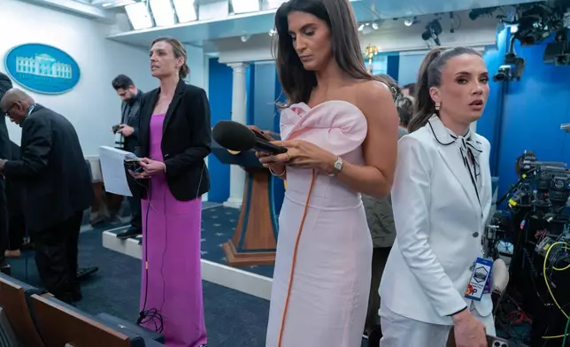 Reporters dressed in evening gowns gala wait for President Donal Trump to speak in the James Brady Press Briefing Room at the White House after a shooting incident outside the ballroom at at the annual White House Correspondents' Association dinner in Washington, Saturday, April 25, 2026. (AP Photo/Jose Luis Magana)