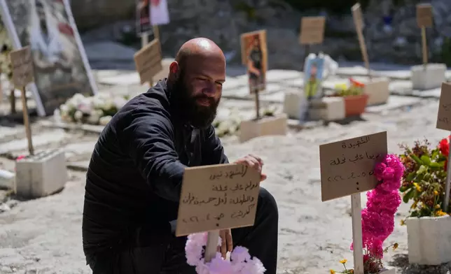 Hussein Farran whose six members of his family were killed in a Israeli airstrike in Kfar Hatta village, visits their graves at a cemetery where civilians and Hezbollah fighters are temporary buried in the southern port city of Sidon, Lebanon, Tuesday, April 14, 2026. (AP Photo/Mohammed Zaatari)