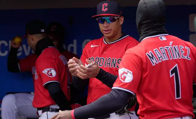 Cleveland Guardians Juan Brito, left, holds hand warmers in the dugout as he talks with center fielder Angel Martínez (1) in the dugout before a baseball game against the Kansas City Royals in Cleveland, Tuesday, April 7, 2026. (AP Photo/Sue Ogrocki)