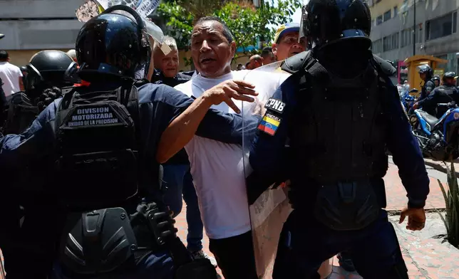 Bolivarian National Police stop protesters who are demanding higher salaries, pensions and benefits, from continuing their march to the Miraflores Presidential Palace in Caracas, Venezuela, Thursday, April 9, 2026. (AP Photo/Pedro Mattey)