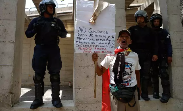 Bolivarian National Police flank a protester who is taking part in a march demanding higher salaries, pensions and benefits, in Caracas, Venezuela, Thursday, April 9, 2026. (AP Photo/Pedro Mattey)