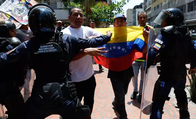 Bolivarian National Police stop protesters who are demanding higher salaries, pensions and benefits, from continuing their march to the Miraflores Presidential Palace in Caracas, Venezuela, Thursday, April 9, 2026. (AP Photo/Pedro Mattey)