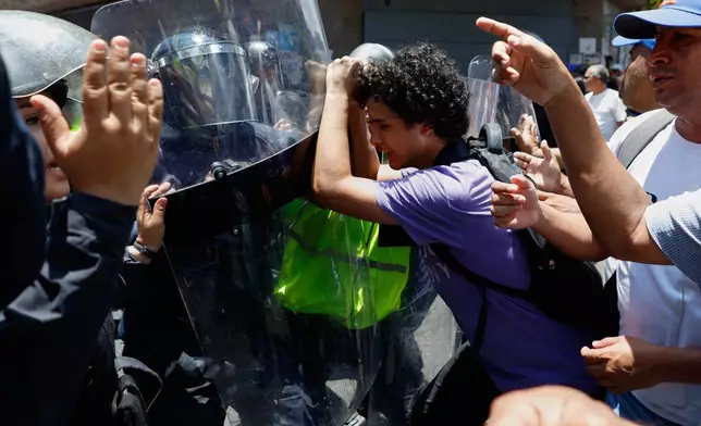 Bolivarian National Police prevent protesters who are demanding higher salaries, pensions and benefits, from continuing their march to the Miraflores Presidential Palace in Caracas, Venezuela, Thursday, April 9, 2026. (AP Photo/Pedro Mattey)