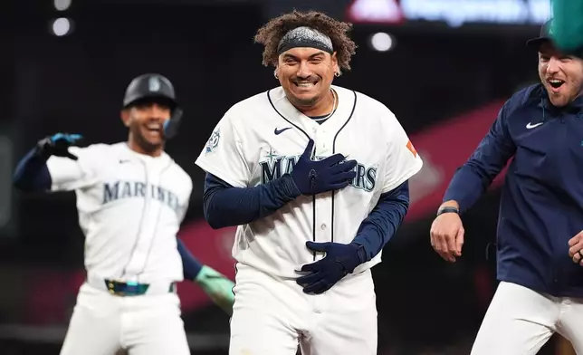 Seattle Mariners' Josh Naylor, center, celebrates with Julio Rodríguez, left, and Luke Raley, right, after hitting a game-winning single against the Athletics during the ninth inning of a baseball game, Wednesday, April 22, 2026, in Seattle. (AP Photo/Lindsey Wasson)