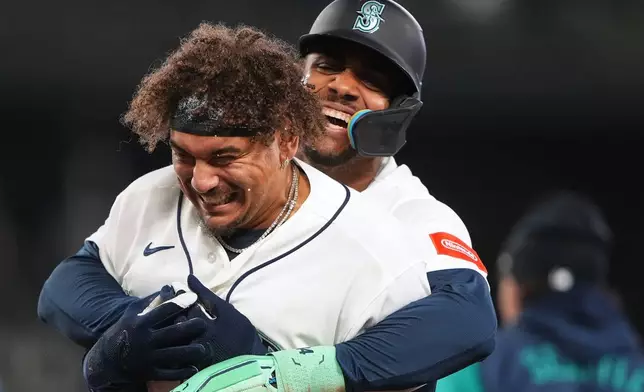 Seattle Mariners' Josh Naylor, front, is hugged by Julio Rodríguez, back, as they celebrate Naylor's game-winning single against the Athletics during the ninth inning of a baseball game, Wednesday, April 22, 2026, in Seattle. (AP Photo/Lindsey Wasson)