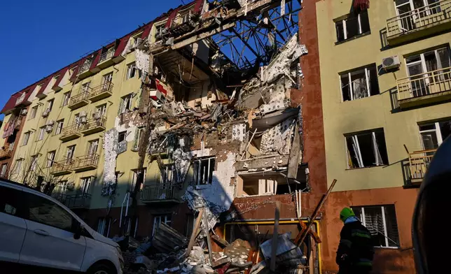 A rescue worker walks in front of residential building which was heavily damaged after a Russian strike in Odesa, Ukraine, Monday, April 6, 2026. (AP Photo/Michael Shtekel)