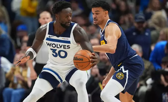 Minnesota Timberwolves forward Julius Randle, left, looks to drive past Denver Nuggets forward Spencer Jones, right, in the first half in Game 5 of a first-round NBA playoffs basketball series Monday, April 27, 2026, in Denver. (AP Photo/David Zalubowski)