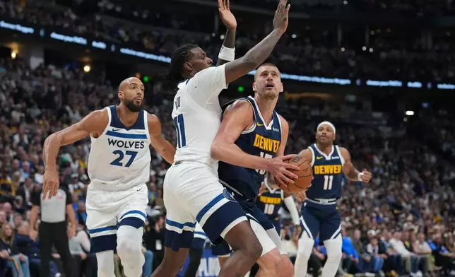 Denver Nuggets center Nikola Jokic, front right, drives the lane as Minnesota Timberwolves centers Naz Reid, center left, and Rudy Gobert, left, defend in the first half in Game 5 of a first-round NBA playoffs basketball series Monday, April 27, 2026, in Denver. (AP Photo/David Zalubowski)