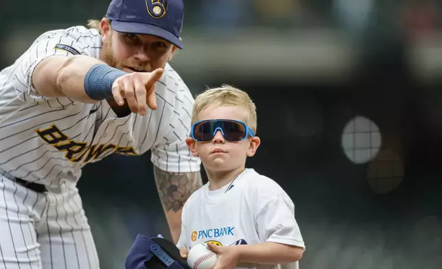 Milwaukee Brewers first baseman Jake Bauers (9) points a small boy back to the stands after signing an autograph before the first inning of a baseball game against the Pittsburgh Pirates Sunday, April 26, 2026, in Milwaukee. (AP Photo/Jeffrey Phelps)