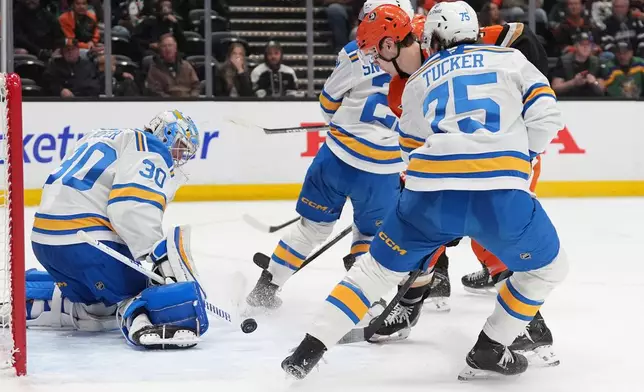St. Louis Blues goaltender Joel Hofer (30) blocks a shot from Anaheim Ducks right wing Beckett Sennecke, center, as St. Louis Blues defenseman Tyler Tucker (75) defends during the third period of an NHL hockey game Friday, April 3, 2026, in Anaheim, Calif. (AP Photo/Gregory Bull)