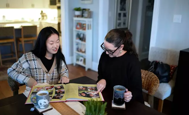 Zoie Albers and her adoptive mother, Leslie Albers, right, look through family photographs at their home in Piperton, Tenn., on Saturday, Jan. 17, 2026. (AP Photo/George Walker IV)