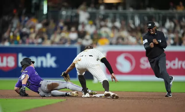 Colorado Rockies' Jake McCarthy, left, is tagged out by San Diego Padres shortstop Xander Bogaerts after trying to advance to second off a single as umpire Edwin Moscoso makes the call, right, during the fifth inning of a baseball game Thursday, April 9, 2026, in San Diego. (AP Photo/Gregory Bull)