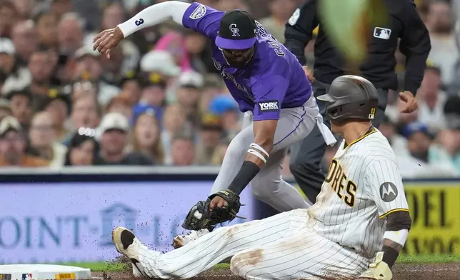 San Diego Padres' Manny Machado, right, safely steals third base as Colorado Rockies third baseman Willi Castro is late with the tag during the sixth inning of a baseball game Thursday, April 9, 2026, in San Diego. (AP Photo/Gregory Bull)