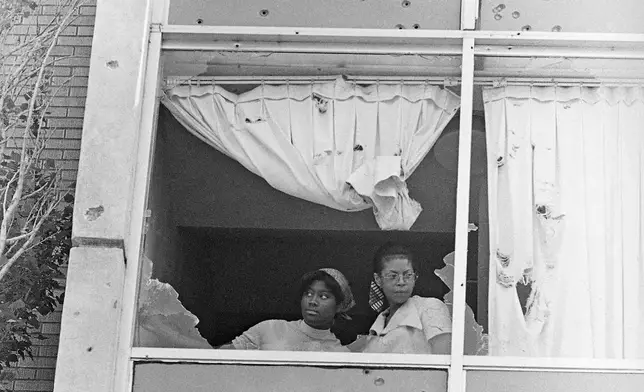 FILE - Students at Jackson State College peer from a window that was shot out by police on campus May 15, 1970. Two youths died as police riddled windows of a girl's dormitory they claimed they were returning sniper fire. (AP Photo/Jack Thornell, File)