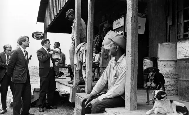 FILE - Sen. Robert F. Kennedy, D-N.Y., left, talks with a group of people in front of a country store during his tour of the Mississippi Delta, while investigating the federal antipoverty program, near Greenville, Miss., April 11, 1967. Next to Kennedy is Kenneth Dean of the Mississippi Council on Human Relations, who is holding a child suffering from a diet deficiency. (AP Photo/Jack Thornell, File)