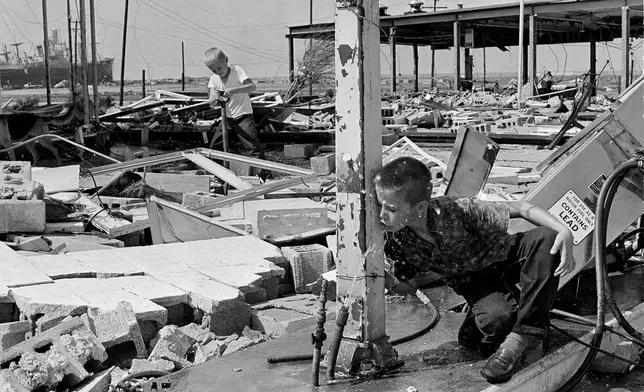 FILE - Carl Wright drinks from a broken pipe amid the ruins of his father's service station in Gulfport, Miss., in the aftermath of Hurricane Camille. (AP Photo/Jack Thornell, File)