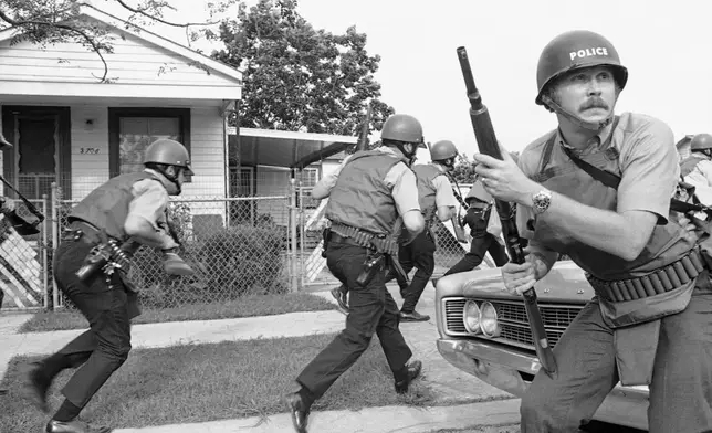 FILE - New Orleans police officers try to keep their heads down as they move in on a Black Panther headquarters during an exchange of gunfire in New Orleans, Sept. 15, 1970. (AP Photo/Jack Thornell, File)