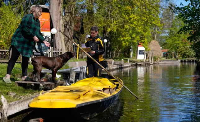 Mailwoman Andrea Bunar delivers mail from a boat during the first tour of the summer when mail delivered on the waterways in the village Lehde in Luebbenau, Germany, Wednesday, April 29, 2026. (AP Photo/Markus Schreiber)
