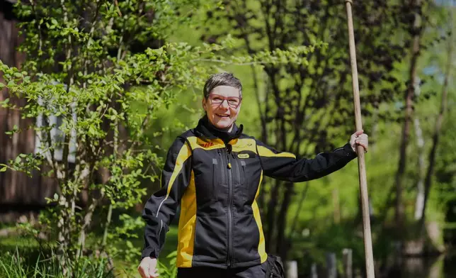 Mailwoman Andrea Bunar stands on a boat, using one long oar to row, steer, and navigate the barge through narrow waterways during the first tour of the summer when mail delivered on the waterways in the village Lehde in Luebbenau, Germany, Wednesday, April 29, 2026. (AP Photo/Markus Schreiber)