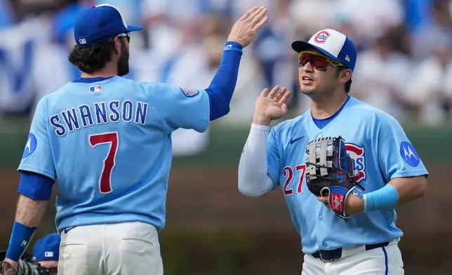 Chicago Cubs' Dansby Swanson (7) and Seiya Suzuki (27) celebrate their team's win over the New York Mets in a baseball game Friday, April 17, 2026, in Chicago. (AP Photo/Erin Hooley)