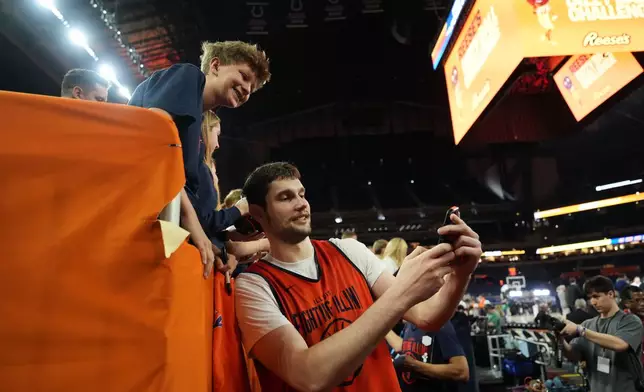 Illinois' Tomislav Ivisic takes a selfie with a fan following practice ahead of a national semifinal NCAA college basketball tournament game against UConn at the Final Four, Friday, April 3, 2026, in Indianapolis. (AP Photo/Michael Conroy)