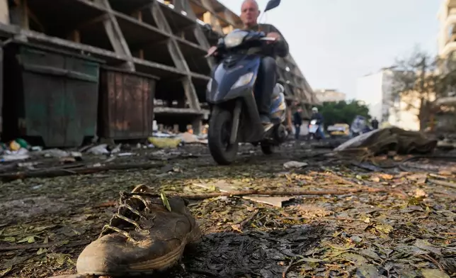 A shoe lies amid debris as a man rides a scooter past the site of an Israeli strike in Beirut, Lebanon, Wednesday, April 1, 2026. (AP Photo/Hassan Ammar)