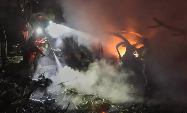 Rescue workers inspect the scene of an Israeli airstrike as fires burn among damaged vehicles, in Beirut, Lebanon, Wednesday, April 1, 2026. (AP Photo/Hussein Malla)