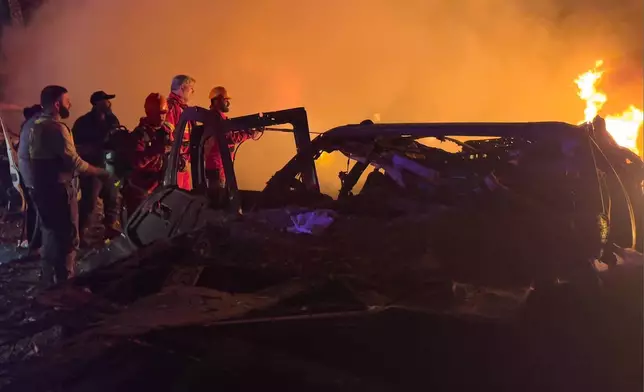 Rescue workers inspect the scene of an Israeli airstrike as fires burn among damaged vehicles, in Beirut, Lebanon, Wednesday, April 1, 2026. (AP Photo/Hussein Malla)