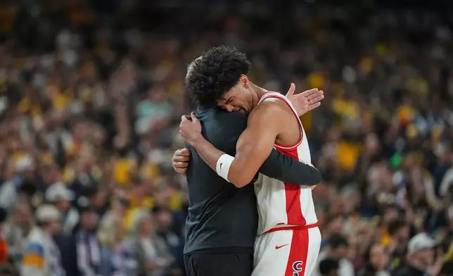 Arizona's Koa Peat, right, hugs head coach Tommy Lloyd near the end of an NCAA college basketball tournament semifinal game against Arizona at the Final Four, Saturday, April 4, 2026, in Indianapolis. (AP Photo/Michael Conroy)