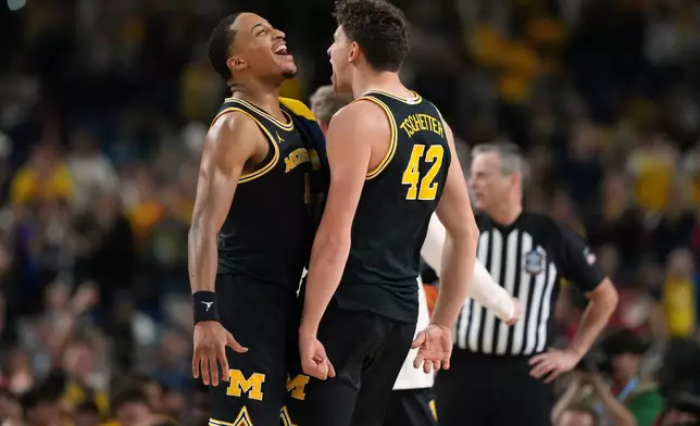 Michigan's Nimari Burnett, left, and Will Tschetter (42) celebrate during the second half of an NCAA college basketball tournament semifinal game against Arizona at the Final Four, Saturday, April 4, 2026, in Indianapolis. (AP Photo/Michael Conroy)