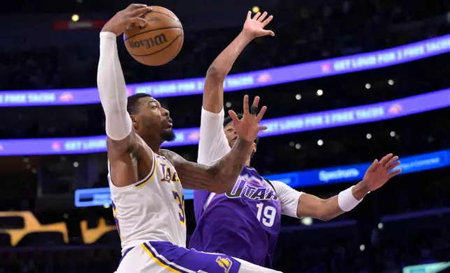 Los Angeles Lakers guard Marcus Smart is defended by Utah Jazz guard Ace Bailey (19) as he drives to the basket during the first half of an NBA basketball game Sunday, April 12, 2026, in Los Angeles. (AP Photo/Jayne Kamin-Oncea)