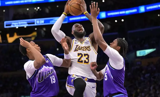 Los Angeles Lakers forward LeBron James (23) is defended by Utah Jazz guard Ace Bailey, left, and Jazz forward Cody Williams as he drives to the basket during the first half of an NBA basketball game Sunday, April 12, 2026, in Los Angeles. (AP Photo/Jayne Kamin-Oncea)