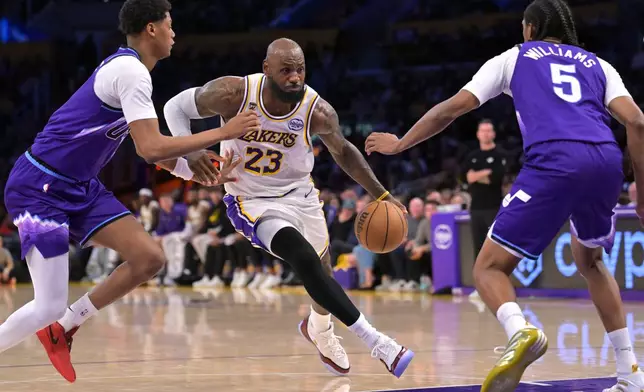 Los Angeles Lakers forward LeBron James (23) is defended by Utah Jazz guard Ace Bailey, left, and Jazz forward Cody Williams as he drives to the basket during the first half of an NBA basketball game Sunday, April 12, 2026, in Los Angeles. (AP Photo/Jayne Kamin-Oncea)