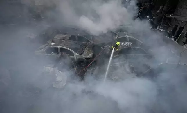 A firefighter sprays smoldering debris at the site of an Israeli airstrike that struck an apartment building in Beirut, Lebanon, Wednesday, April 8, 2026. (AP Photo/Bilal Hussein)