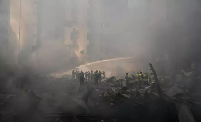 Firefighters, volunteers and first responders walk on smoldering debris at the site of an Israeli airstrike that struck a building in Beirut, Lebanon, Wednesday, April 8, 2026. (AP Photo/Hassan Ammar)