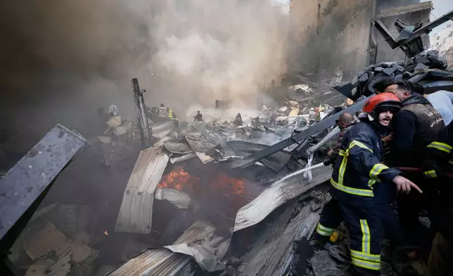 Firefighters, first responders, and volunteers work on smoldering debris at the site of an Israeli airstrike that struck an apartment building in Beirut, Lebanon, Wednesday, April 8, 2026. (AP Photo/Bilal Hussein)