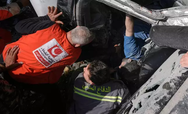 First responders try to rescue a man trapped in a car at the site of an Israeli airstrike in Beirut, Lebanon, Wednesday, April 8, 2026. (AP Photo/Bilal Hussein)