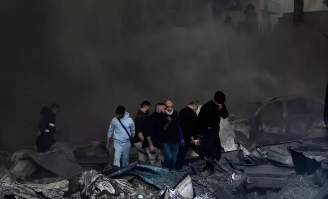 First responders and volunteers emerge through the smoke at the site of an Israeli airstrike that struck an apartment building in Beirut, Lebanon, Wednesday, April 8, 2026. (AP Photo/Bilal Hussein)
