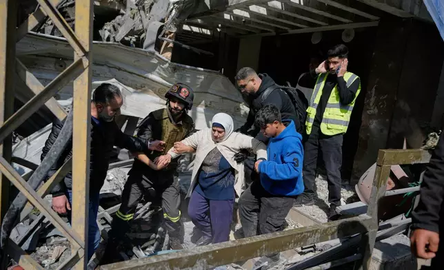 A woman is assisted to leave a destroyed building at the site of an Israeli airstrike that struck an apartment building in Beirut, Lebanon, Wednesday, April 8, 2026. (AP Photo/Bilal Hussein)