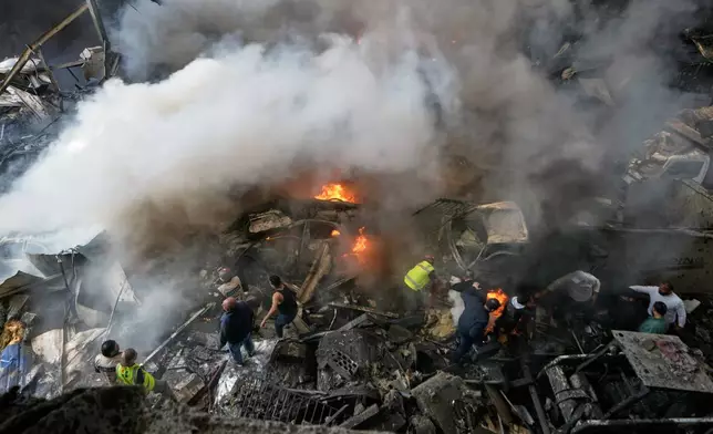 First responders and volunteers search through the rubble beside burning cars at the site of an Israeli airstrike that struck an apartment building in Beirut, Lebanon, Wednesday, April 8, 2026. (AP Photo/Bilal Hussein)