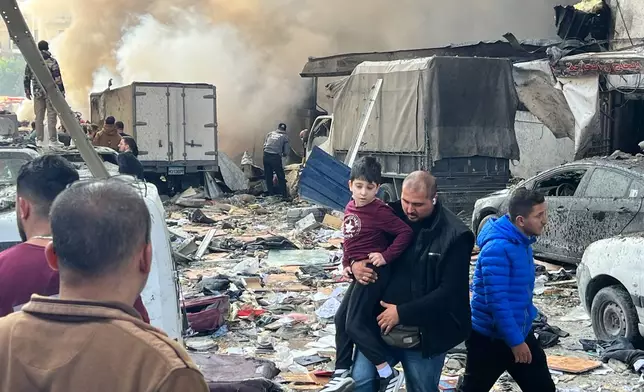 A man holds a child as they leave the site of an Israeli airstrike that struck an apartment building in Beirut, Lebanon, Wednesday, April 8, 2026. (AP Photo/Hussein Malla)