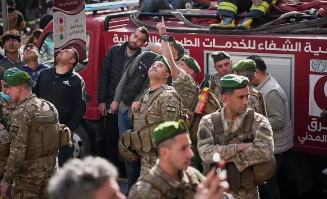 Lebanese army soldiers and first responders look up at an Israeli drone flying overhead at the site of an Israeli airstrike in Beirut, Lebanon, Wednesday, April 8, 2026. (AP Photo/Emilio Morenatti)