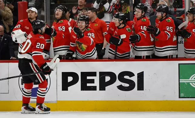 Chicago Blackhawks' Ryan Greene (20) celebrates with teammates at the bench after scoring during the first period of an NHL hockey game against the Buffalo Sabres in Chicago, Monday, April 13, 2026. (AP Photo/Paul Beaty)